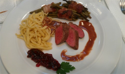 Mittagsgericht mit Spätzle, Fleisch und Preiselbeeren auf weißem Teller